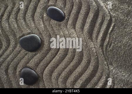 Des dessins sur sable gris clair et les pierres noires dans un petit jardin Zen Banque D'Images