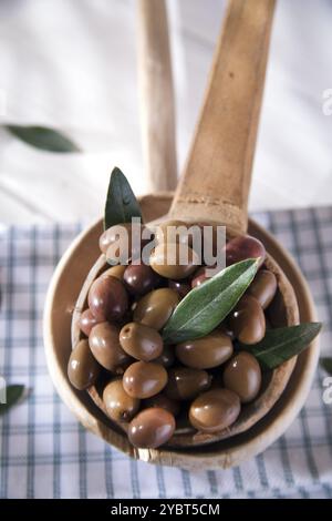 Présentation d'un petit groupe d'olives noires sur une louche en bois Banque D'Images