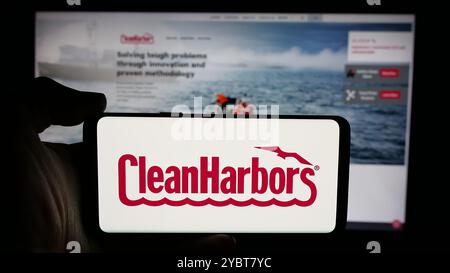 Personne tenant le téléphone portable avec le logo de la société de services américaine Clean Harbors Inc sur l'écran en face de la page Web de l'entreprise. Concentrez-vous sur l'affichage du téléphone. Banque D'Images