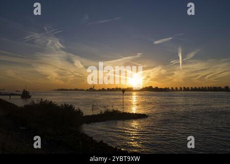 Lever du soleil au-dessus de la rivière Merwede près du village Boven-Hardinxveld dans la région néerlandaise Alblasserwaard Banque D'Images