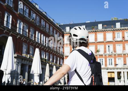 Cycliste non identifié regardant les terrasses fermées de la Plaza Mayor de Madrid pendant le confinement du coronavirus Banque D'Images