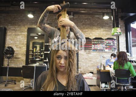 Femme ayant ses cheveux coiffés dans un salon de coiffure hipster Banque D'Images