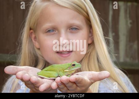 Jeune fille caucasienne pré adolescente tenant une grenouille d'arbre à lèvres blanches dans ses mains thèmes de l'imagination histoires magiques enfance Banque D'Images