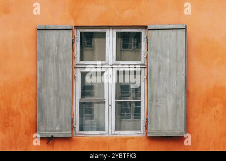 Vieux volets de fenêtre en bois d'une maison européenne avec façade peinte en orange, fond vintage Banque D'Images