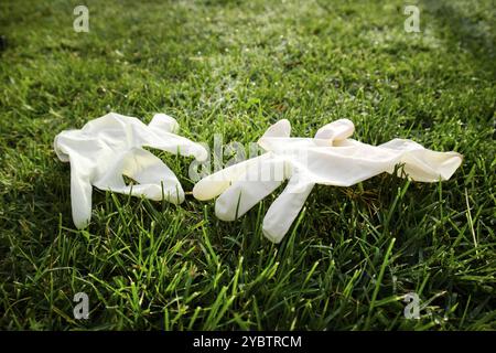 Représentation photographique d'une paire de gants jetables anti-Coronavirus jetés dans le sol causant de la pollution Banque D'Images