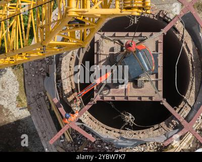 Travaillez sur le dessus de la cheminée. Une excavatrice suspendue sur une grue détruit une cheminée. Vue aérienne drone de démolition de cheminée, excavatrice travaillant sur la fumée Banque D'Images