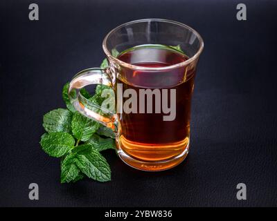 Un verre avec poignée contenant du thé à base de feuilles de menthe fraîches Banque D'Images