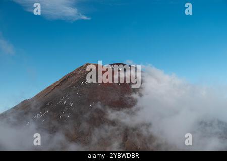 Vue du volcan Mont Ngauruhoe avec brouillard roulant sur la montagne et ciel cristallin (Tongariro Crossing, Île du Nord, Nouvelle-Zélande) Banque D'Images