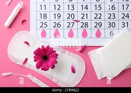 Composition de pose plate avec calendrier et produits menstruels sur fond rose Banque D'Images