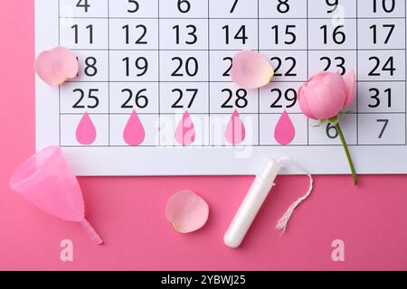 Composition de pose plate avec calendrier et produits menstruels sur fond rose Banque D'Images