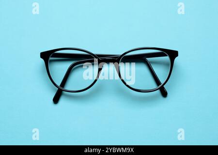 Paire de lunettes lunettes lunettes pliées sur fond bleu cyan vue de dessus Banque D'Images