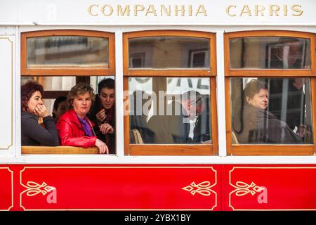 Lisbonne, Portugal, 1er mars 2007, Un groupe de personnes regarde par la fenêtre en voyageant dans un tramway rouge autour de Lisbonne, trempant dans le paysage urbain. Banque D'Images