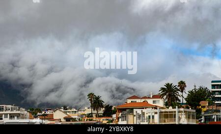 Nuages spectaculaires descendant sur les montagnes avec vue sur Puerto de la Cruz, Tenerife, et maisons résidentielles au premier plan. Banque D'Images