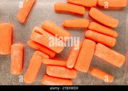 Petites carottes pelées sur un plateau en métal, macro, vue de dessus. Banque D'Images