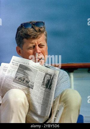 Le président américain John F. Kennedy fumant un cigare et lisant le journal tout en étant assis à bord du yacht présidentiel, « Honey Fitz », pendant le week-end de la fête du travail, Hyannis Port, Massachusetts, États-Unis, Cecil Stoughton, photographies de la Maison Blanche, 31 août 1963 Banque D'Images