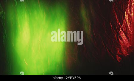 Texture de feuille d'aluminium froissée. Superposition de lumière parasite. Couleur vert néon défocalisé lueur sur papier vieilli froissé brillant or rouge avec rayures de poussière fond abstrait. Banque D'Images