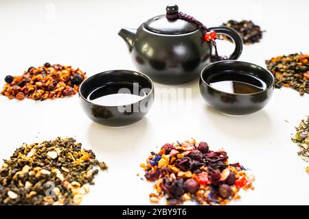 Assorti différents types de thé et une théière avec des tasses sur une table blanche. Photo de haute qualité Banque D'Images