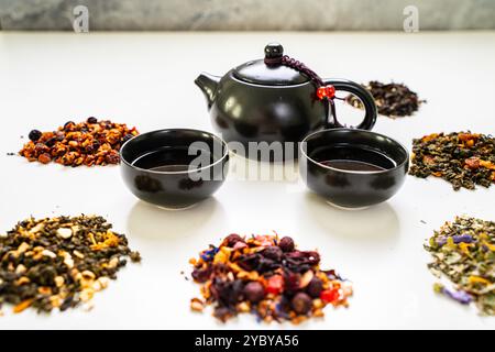 Assorti différents types de thé et une théière avec des tasses sur une table blanche. Photo de haute qualité Banque D'Images