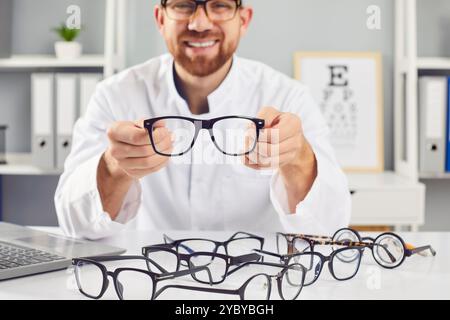 Ophtalmologiste montrant des lunettes, médecin souriant en clinique, aidant à choisir une vision médicale correcte Banque D'Images