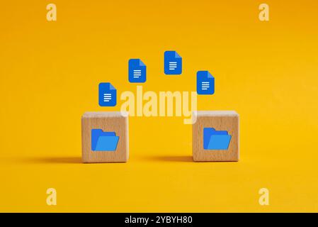 Processus de transfert de données ou de fichiers entre dossiers. Icônes de document volant dans le dossier numérique sur des cubes en bois sur fond jaune. Banque D'Images