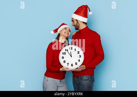 Un couple célèbre le compte à rebours du nouvel an tout en portant des chapeaux festifs Banque D'Images