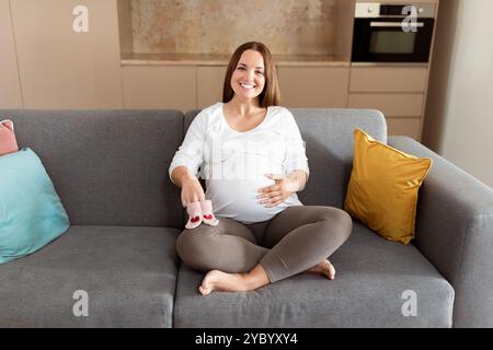 Future mère assise confortablement sur un canapé dans une maison moderne Banque D'Images