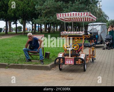 Batumi, Géorgie. 08.03.2024 loueur de véhicules. Fauteuil roulant pour l'équitation dans le parc. Divertissement au Resort. Résident local attendant une coutume Banque D'Images