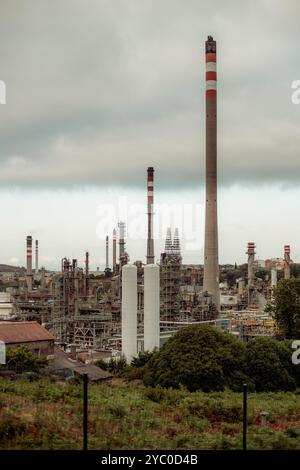 Une photo téléphoto verticale d'une raffinerie de pétrole industriel avec plusieurs cheminées et tours de refroidissement émettant des fumées. Réseau complexe de tuyaux, machines, Banque D'Images