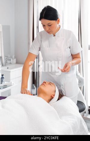 Femme cosmétologue massant l'épaule du client au salon de beauté. La cliente féminine détendue se fait dorloter dans le spa par une esthéticienne professionnelle. Banque D'Images
