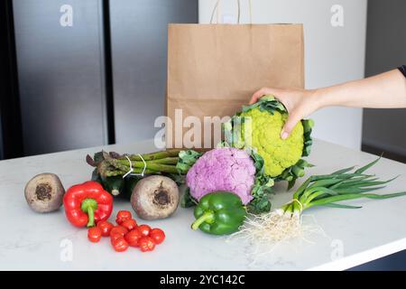 La main de la femme prend le chou-fleur des légumes sur la table de cuisine Banque D'Images