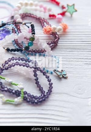 Divers bracelets et accessoires colorés en perles faits à la main sont disposés sur une surface en bois rustique, mettant en valeur la créativité et l'artisanat dans les bijoux Banque D'Images