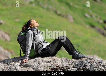 Randonneur se reposant et se relaxant avec les yeux fermés assis sur un rocher dans la montagne Banque D'Images