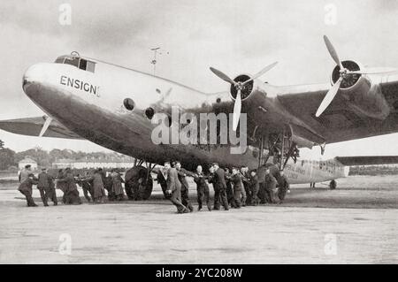 Un « Ensign » d'Imperial Airways est déplacé sur la piste par le personnel au sol du R.A.F. 1938. Tiré de Wings of War, publié en 1942. Banque D'Images