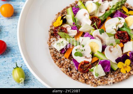 Salade de quinoa avec champignons, œufs et tomates séchées servies sur une assiette en porcelaine blanche Banque D'Images