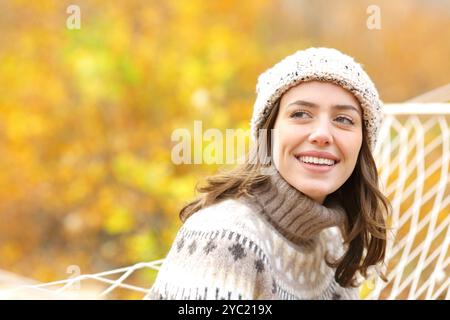 Belle femme heureuse dans la forêt d'automne regardant le côté assis sur le hamac Banque D'Images