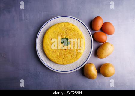 Une délicieuse omelette de pommes de terre espagnole, faite avec des œufs et des pommes de terre, magnifiquement présentée sur une table en béton bleu gris vue de dessus Banque D'Images