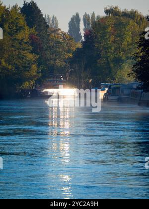 Une péniche amarrée par la Tamise à Abingdon, reflétant le soleil bas par un matin d'automne brumeux. Abingdon prétend être la plus ancienne ville d'Angleterre, et la Tamise traverse son cœur. Si vous faites une promenade en rivière ou du jogging la plupart des jours, vous pouvez souvent attraper des moments transitoires merveilleux et des effets de lumière comme celui-ci. Banque D'Images