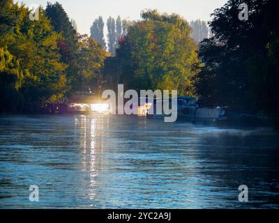 Une péniche amarrée par la Tamise à Abingdon, reflétant le soleil bas par un matin d'automne brumeux. Abingdon prétend être la plus ancienne ville d'Angleterre, et la Tamise traverse son cœur. Si vous faites une promenade en rivière ou du jogging la plupart des jours, vous pouvez souvent attraper des moments transitoires merveilleux et des effets de lumière comme celui-ci. Banque D'Images