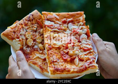 Main coupée servant pizza dans une assiette Banque D'Images