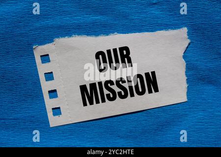 Notre message de mission écrit sur un morceau de papier déchiré déchiré avec un fond bleu. Conceptuel notre symbole de mission. Copier l'espace. Banque D'Images