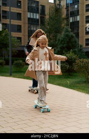 Maman et fille skateboard dans un parc de la ville Banque D'Images