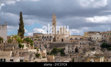 Un moment de tranquillité se déroule à Matera, dans les Pouilles, où des bâtiments historiques en pierre s'élèvent contre un ciel sombre, mettant en valeur l'allure intemporelle de ce captivati Banque D'Images