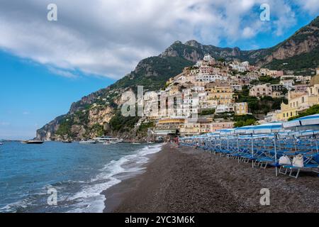 Les vagues tapent doucement contre le rivage sablonneux tandis que les maisons colorées s'accrochent à la colline de Positano, capturant la beauté de la côte amalfitaine. Un esc parfait Banque D'Images