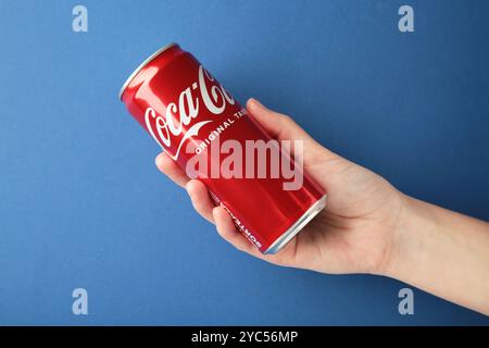 Mykolaiv, Ukraine - 2 mai 2023 : femme tenant une canette de Coca-Cola sur fond bleu. Vue de dessus Banque D'Images