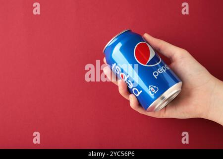 Mykolaiv, Ukraine - 2 mai 2023 : femme tenant une canette de Pepsi sur fond rouge. Vue de dessus Banque D'Images