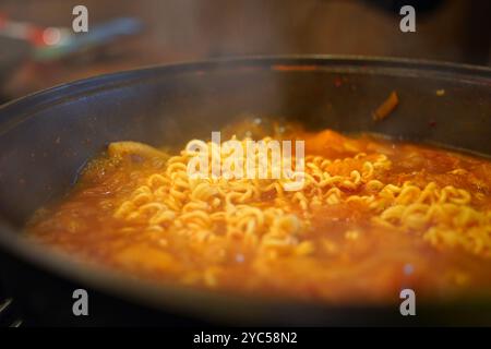 Ajouter les ramen instantanés au bouillon de ragoût kimchi et faire bouillir Banque D'Images