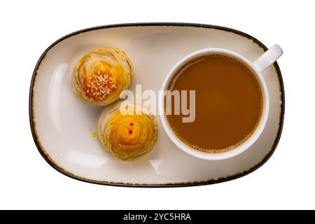 Vue de dessus du café au lait chaud dans une tasse en céramique blanche avec gâteau de lune à pâtisserie chinoise dans un plateau en céramique brun avec bord foncé isolé sur fond blanc avec c. Banque D'Images