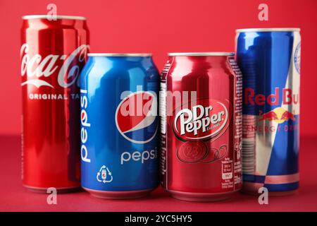 Mykolaiv, Ukraine - 2 mai 2023 : canettes de Coca cola, Pepsi, Dr. Poivre et Red Bull sur fond rouge. Multinationale américaine de boissons. Vue de dessus Banque D'Images