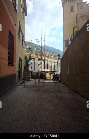 Ruelle étroite avec des cyclomoteurs garés et un pont ferroviaire dans une ville italienne par une journée ensoleillée Banque D'Images