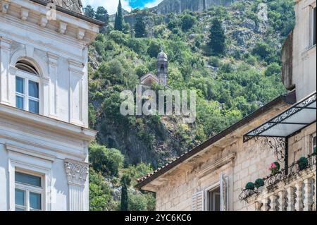 Maisons dans la vieille ville de Kotor avec l'église de notre-Dame de Remedy sur la colline. Banque D'Images